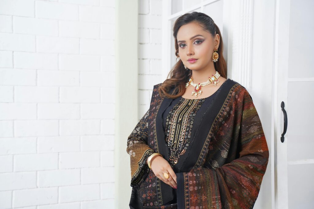 A young woman in traditional Pakistani attire poses elegantly indoors.